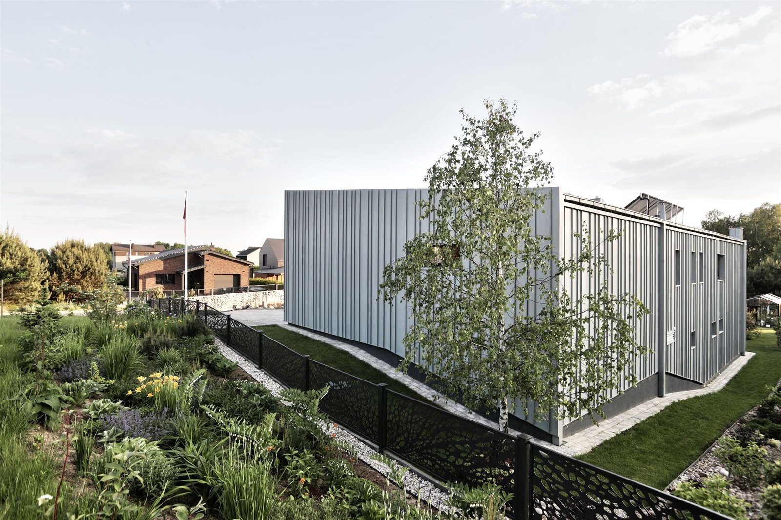 Gyvenamasis namas Tarandėje: gatvės fasadas su vertikalia skarda ir želdiniais